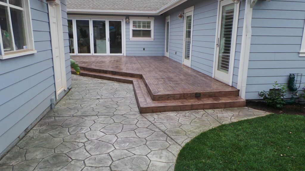 Wood-plank stamped concrete patio with two steps, beside a flagstone-pattern stamped concrete walkway