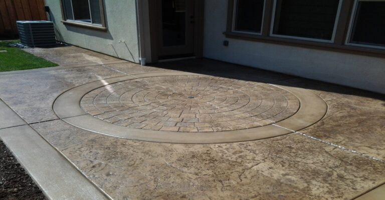 Colored stamped concrete patio with a circular cobblestone medallion and smooth border band