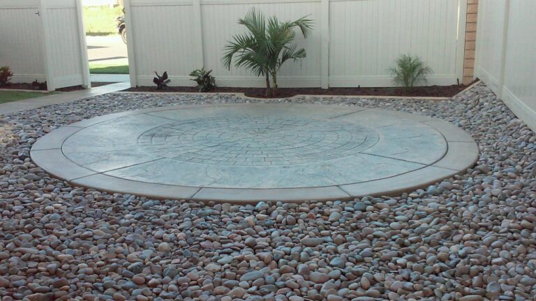 Circular stamped concrete patio with a cobblestone center, set in river rock